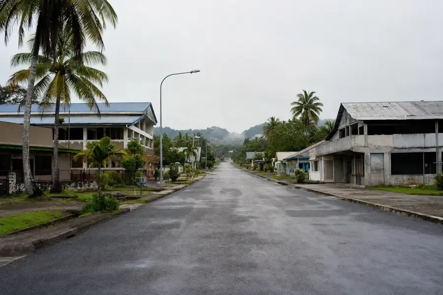 A wide quiet street of low mid-century buildings in a tropical town (AI-generated image)