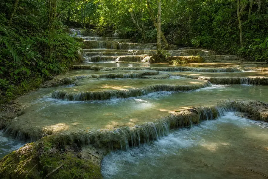 A terraced waterfall stepping down through rainforest in shallow pools (AI-generated image)