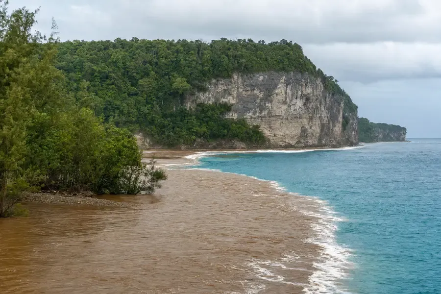 A wide river mouth meeting the sea below grey cliffs (AI-generated image)
