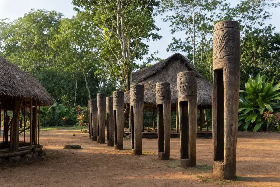 A village ground with tall carved slit drums standing in a row (AI-generated image)